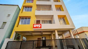 A multi-story building with a yellow facade and a sign for 'OYO ROOMS' indicating a hotel or lodging service.