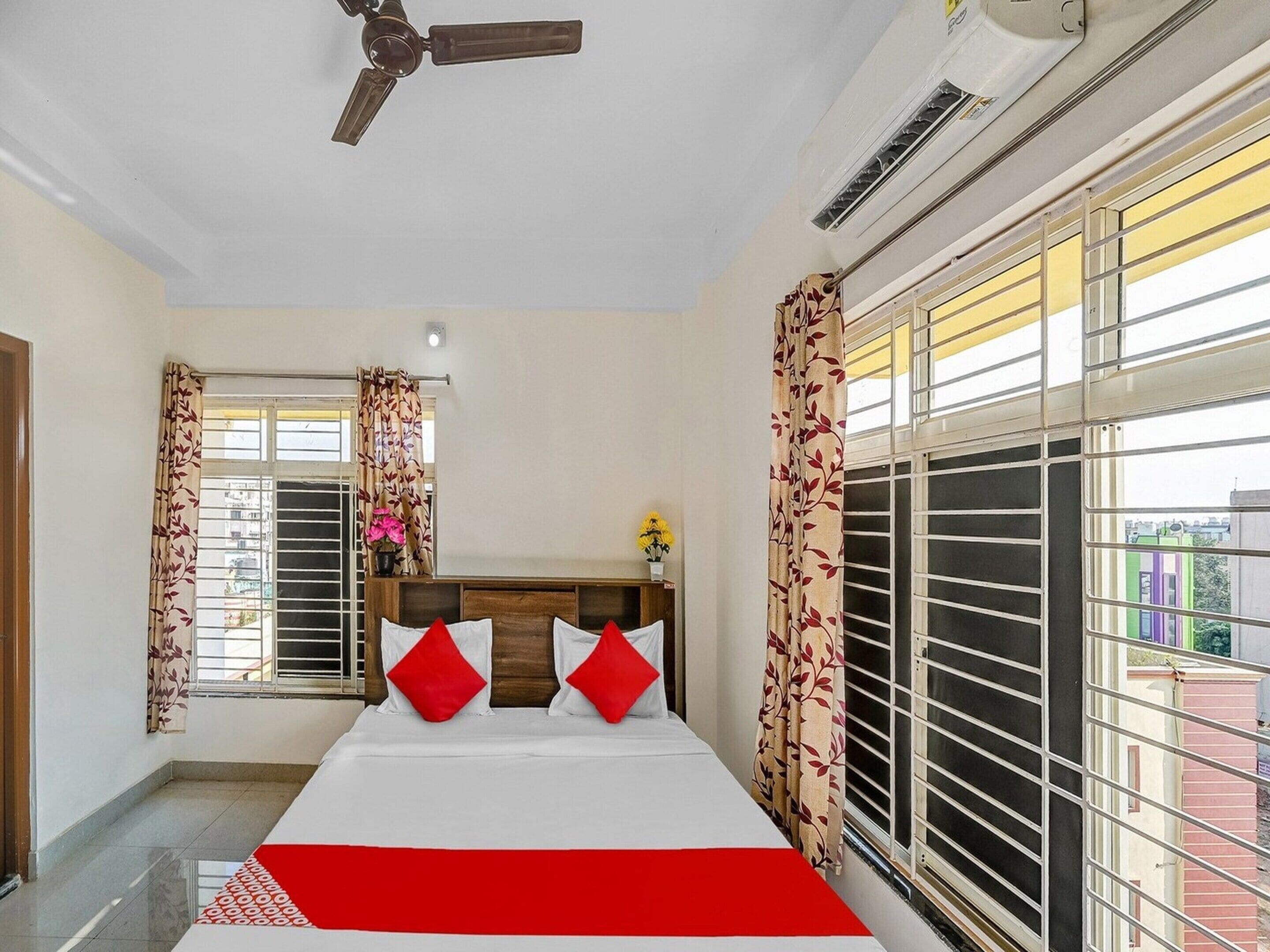 Une chambre d’hôtel équipée d’un lit, de rideaux, d’un ventilateur de plafond et d’un appareil de climatisation.