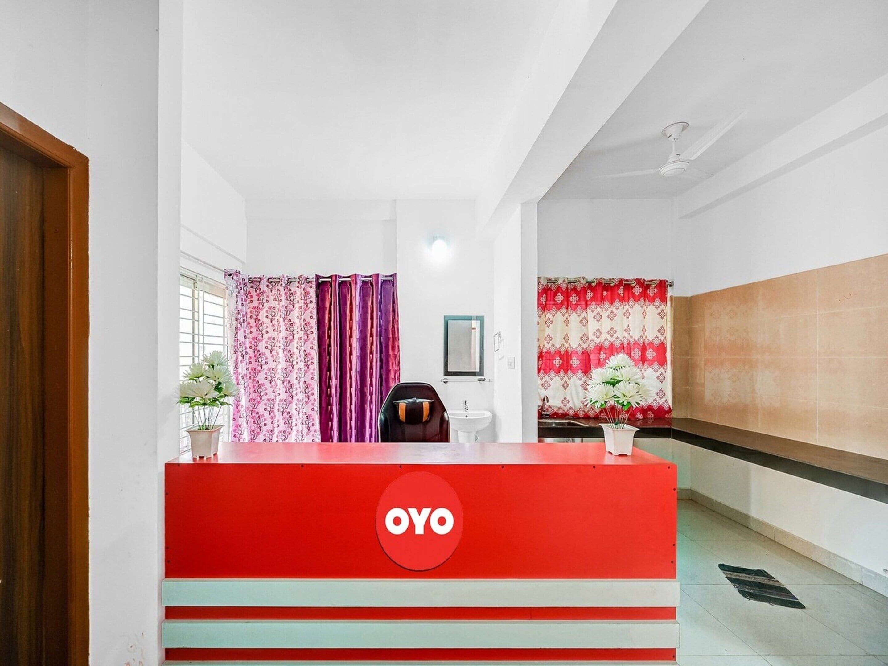 A reception area with a red counter, a white sink, and a chair.