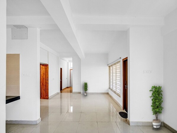 A spacious hallway with white walls, a tiled floor, and doors leading to other rooms. - Classic Dream Marion (Bhubaneshwar)