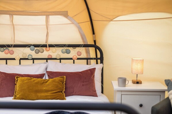 A bed with a headboard, pillows, and a bedside table with a lamp.