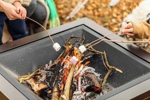 Un feu de camp avec des bûches et des guimauves grillées.