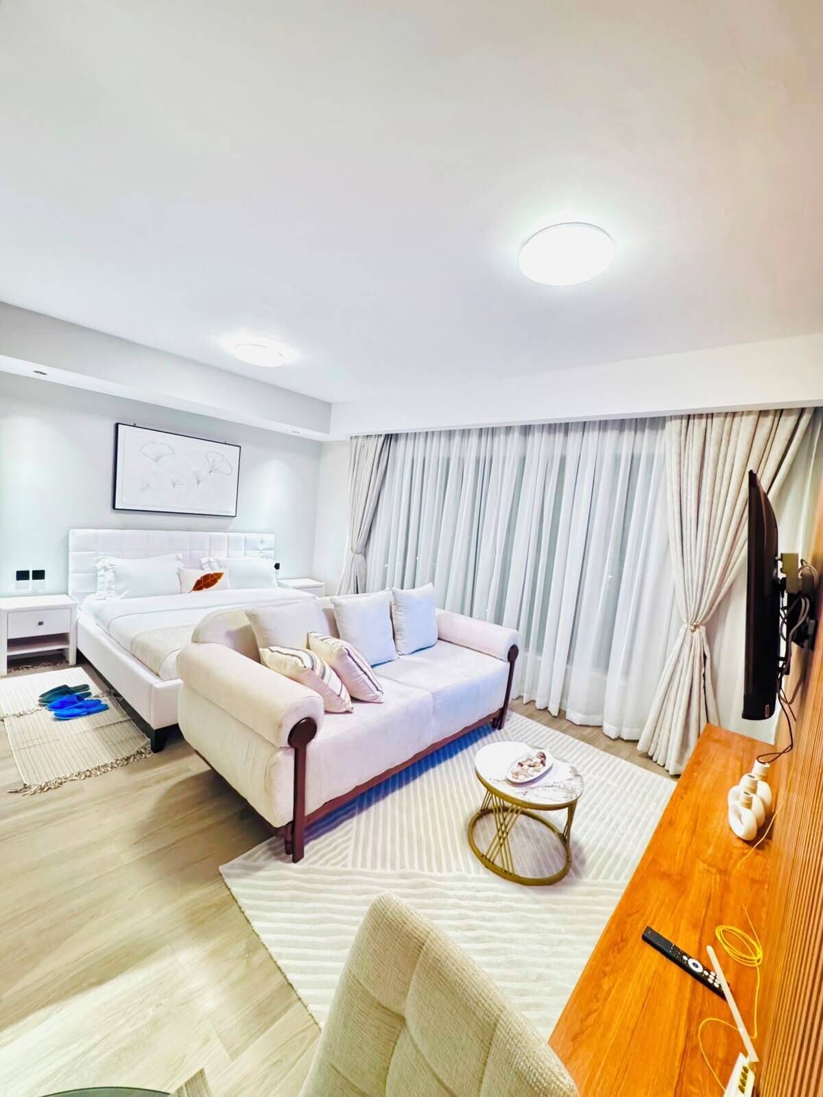 Una habitación de hotel moderna con una cama, un sofá, una mesa de comedor y un televisor.