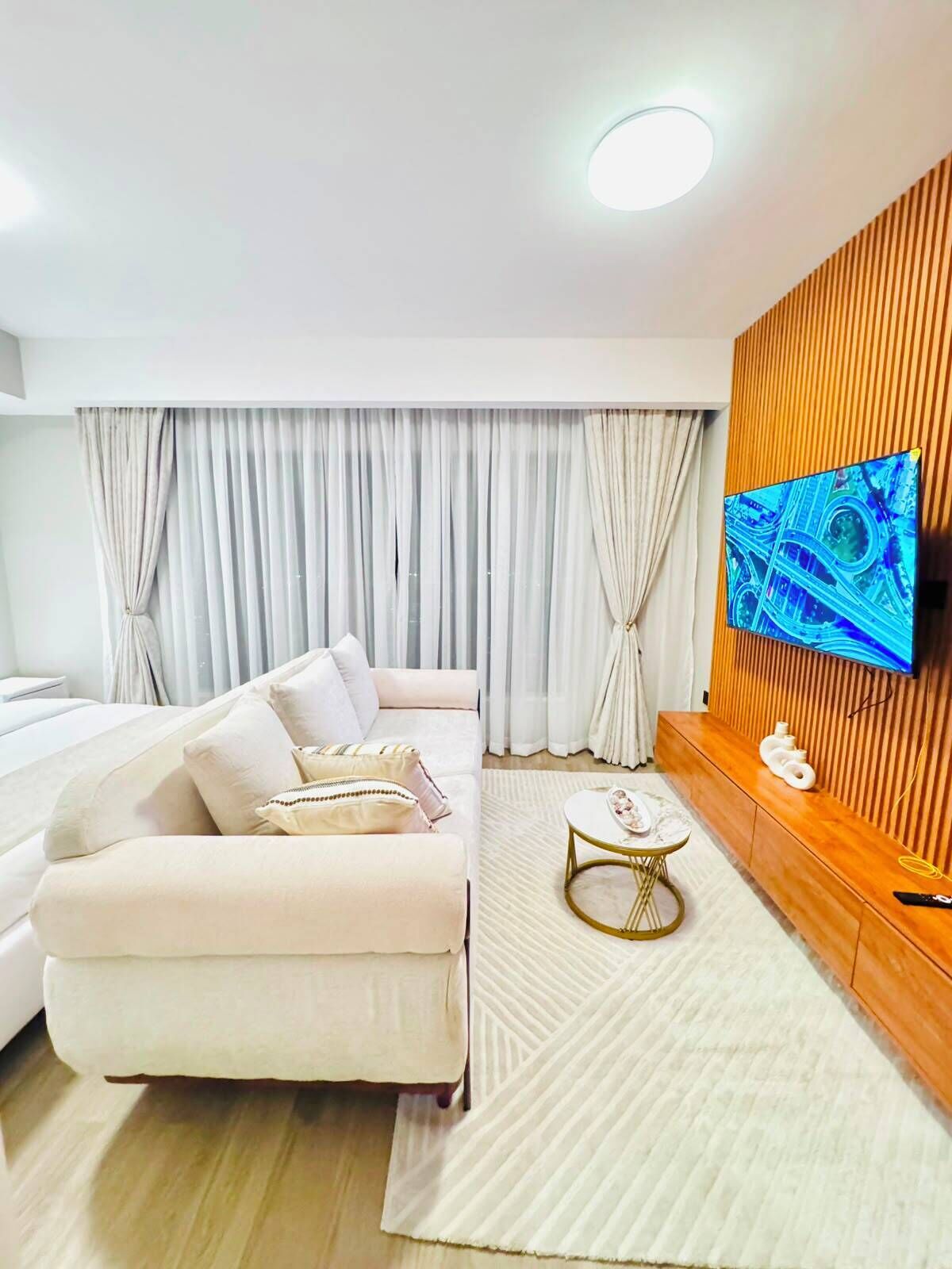 Una sala de estar moderna con un sofá, una mesa de centro y un televisor de pantalla plana montado en una pared de madera.