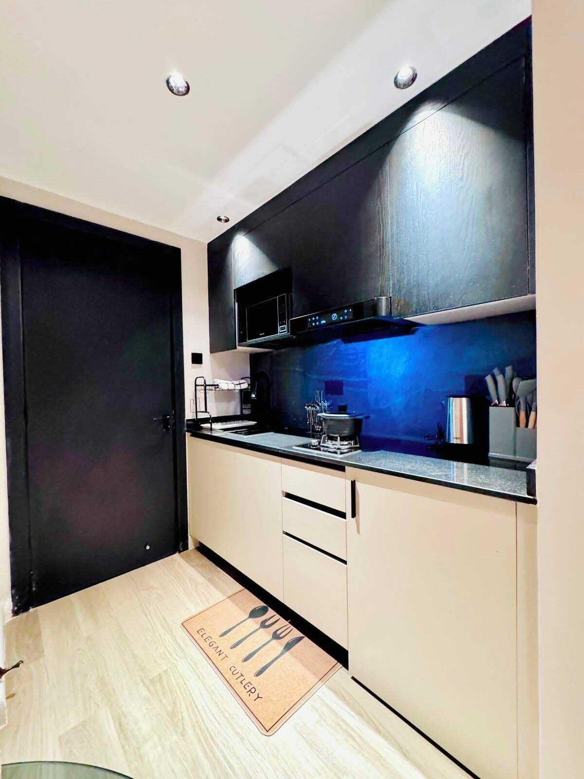 Una cocina moderna con una puerta negra, una campana extractora de acero inoxidable y suelo de madera.