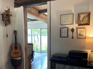 Ein Zimmer mit einer Gitarre, einer Djembe-Trommel, einer Sony-Musikanlage und gerahmten Kunstwerken an der Wand.