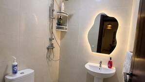 A bathroom with a toilet, sink, shower, and a mirror. - Family Apartment for 4–5 People (Fes)