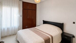 A bedroom with a bed, a nightstand, a wardrobe, and a ceiling light fixture. - Family Apartment for 4–5 People (Fes)