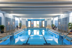 Une piscine intérieure avec des couloirs clairement délimités, des panneaux de signalisation de sécurité et des chaises longues.