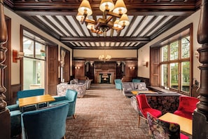 A hotel lobby with a fireplace, multiple seating areas, and large windows.