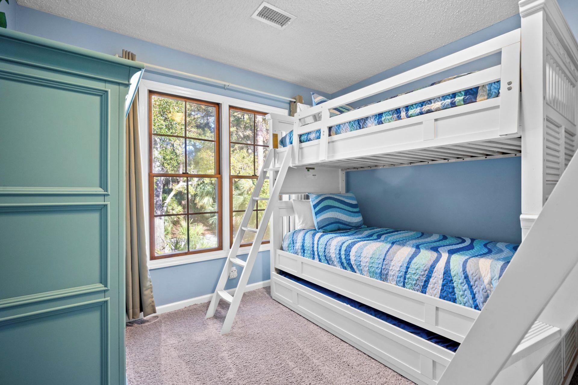 Een slaapkamer met stapelbed, raam, ladder en deur.
