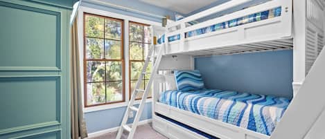 Een slaapkamer met stapelbed, raam, ladder en deur.