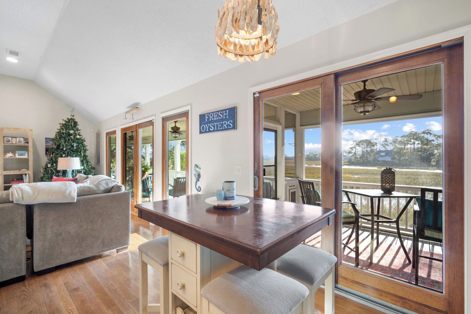 A spacious living area with a wooden dining table, a sofa, and a Christmas tree.