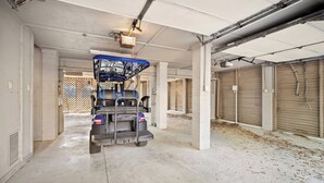 A parking garage with a blue vehicle parked in the center, concrete pillars, and closed garage doors. - Beautiful Marsh Views, Golf Cart Included, Elevator - 364 Blue Gill (Fripp Island)