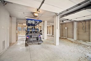 Eine Parkgarage mit einem blauen Fahrzeug in der Mitte, Betonpfeilern und geschlossenen Garagentoren.
