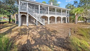 A two-story house with a covered porch and a staircase leading to the upper level. - Beautiful Marsh Views, Golf Cart Included, Elevator - 364 Blue Gill (Fripp Island)