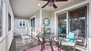A covered porch with a ceiling fan, rocking chairs, a table with chairs, and a rug. - Beautiful Marsh Views, Golf Cart Included, Elevator - 364 Blue Gill (Fripp Island)