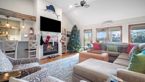 A cozy living room with a fireplace, a Christmas tree, and a large window with a view. - Beautiful Marsh Views, Golf Cart Included, Elevator - 364 Blue Gill (Fripp Island)