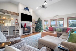 Ein gemütliches Wohnzimmer mit Kamin, Weihnachtstanne und großem Fenster mit Blick.