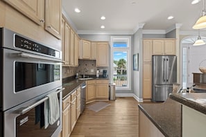 A modern kitchen with stainless steel appliances, wooden cabinets, and a view to the outside. - Walk to the Beach, Elevator, Golf Cart Included - 619 Dolphin Rd (Fripp Island)