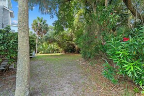 A residential property with a grassy yard, mature trees, and a wooden deck. - Walk to the Beach, Elevator, Golf Cart Included - 619 Dolphin Rd (Fripp Island)