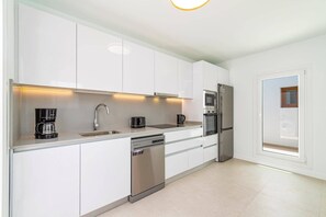 A modern kitchen with white cabinets, stainless steel appliances, and a dishwasher. - Villa Verde Yaiza by Villa Plus (Playa Blanca)