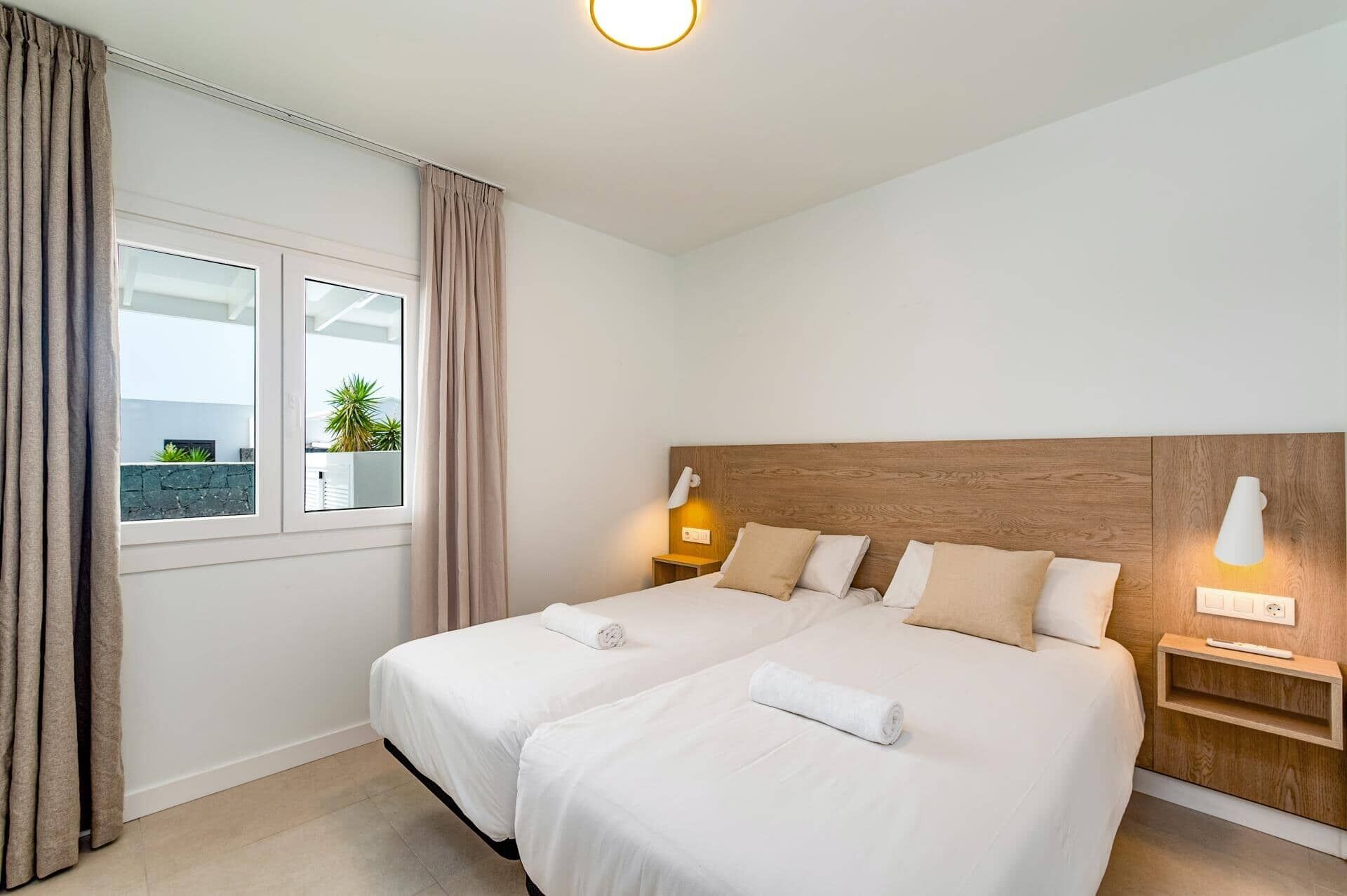 Ett hotellrum med två sängar, ett stort fönster och utsikt över grönområden utanför.