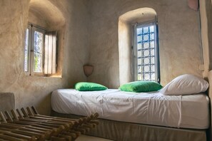 Una habitación con cama, dos ventanas y una lámpara fijada a la pared.