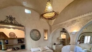 Ein geräumiges Wohnzimmer mit hohen Decken, einem Couchtisch in der Mitte und einer Sofagarnitur.