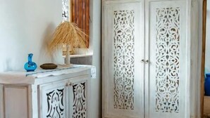 Ein Zimmer mit einem weißen Schrank mit aufwendigen Schnitzereien, einem blauen Teppich und einer weißen Tür mit detaillierten Mustern.