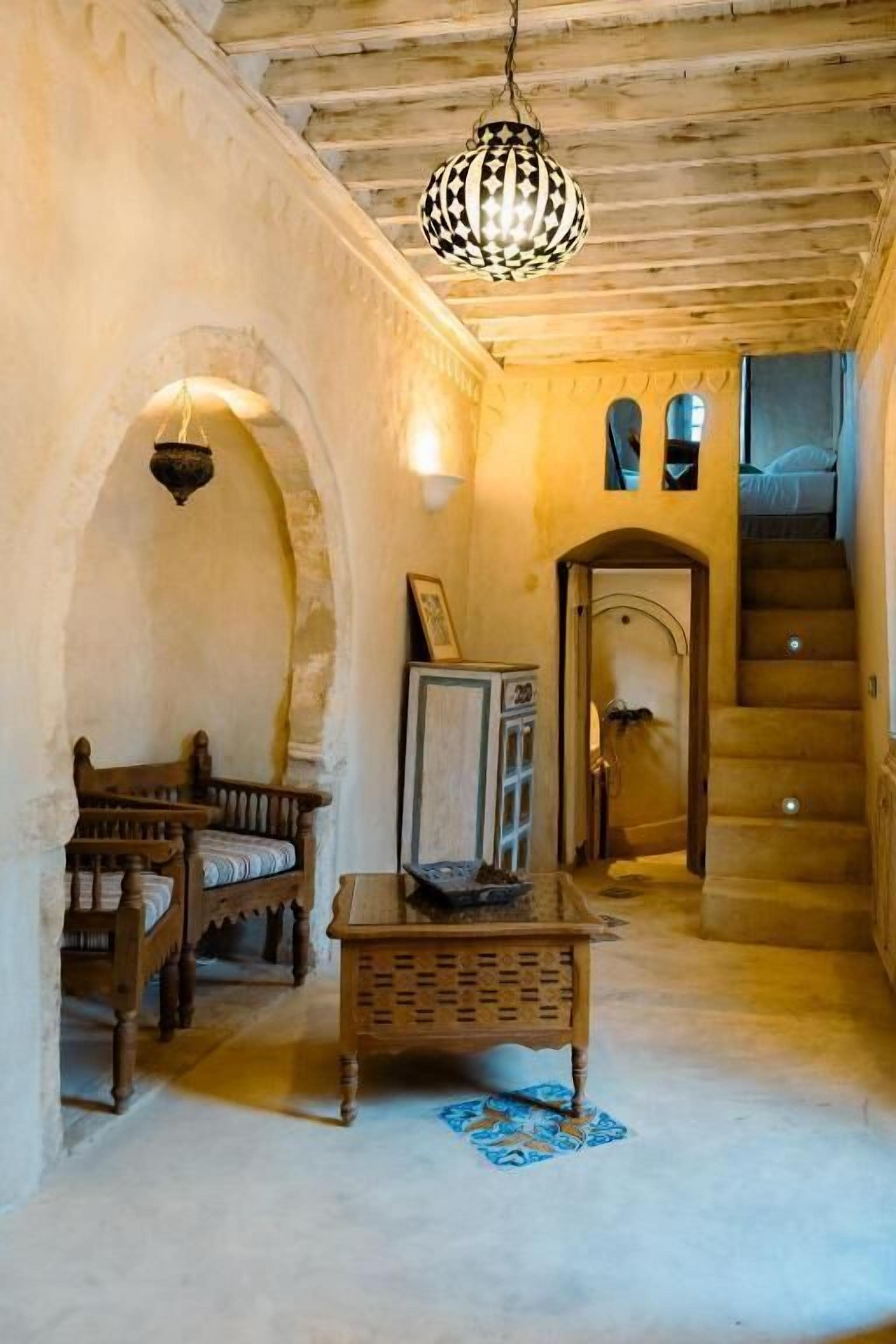 Un interior tradicional con escaleras, muebles de madera y una lámpara colgante.