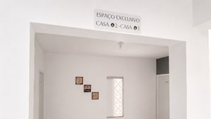 Una habitación amplia con pared blanca, ventana con celosía decorativa y tres cuadros enmarcados.