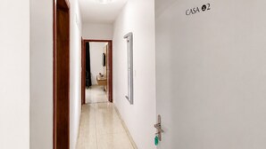 Un pasillo con una puerta que indica 'CASA 2' dando acceso a una habitación.