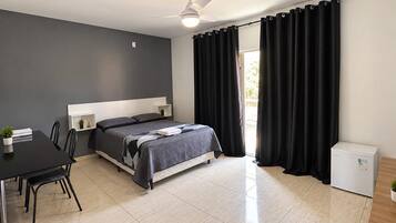 Un dormitorio moderno con cama, escritorio y un refrigerador pequeño.