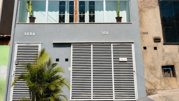 Un edificio con tres banderas, dos ventanas y una puerta.