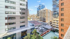 A multi-story building with a flat facade, large windows, and a rooftop terrace with a green roof. - Prime Apartment - MUT y Costanera Center (Las Condes)