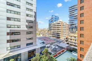 A multi-story building with a flat facade, large windows, and a rooftop terrace with a green roof. - Prime Apartment - MUT y Costanera Center (Las Condes)