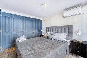A bedroom with a bed, a nightstand, a lamp, a wardrobe, and an air conditioning unit. - Prime Apartment - MUT y Costanera Center (Las Condes)