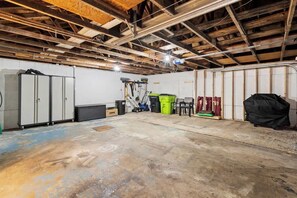 A spacious basement with exposed wooden beams, a workbench, and various tools.