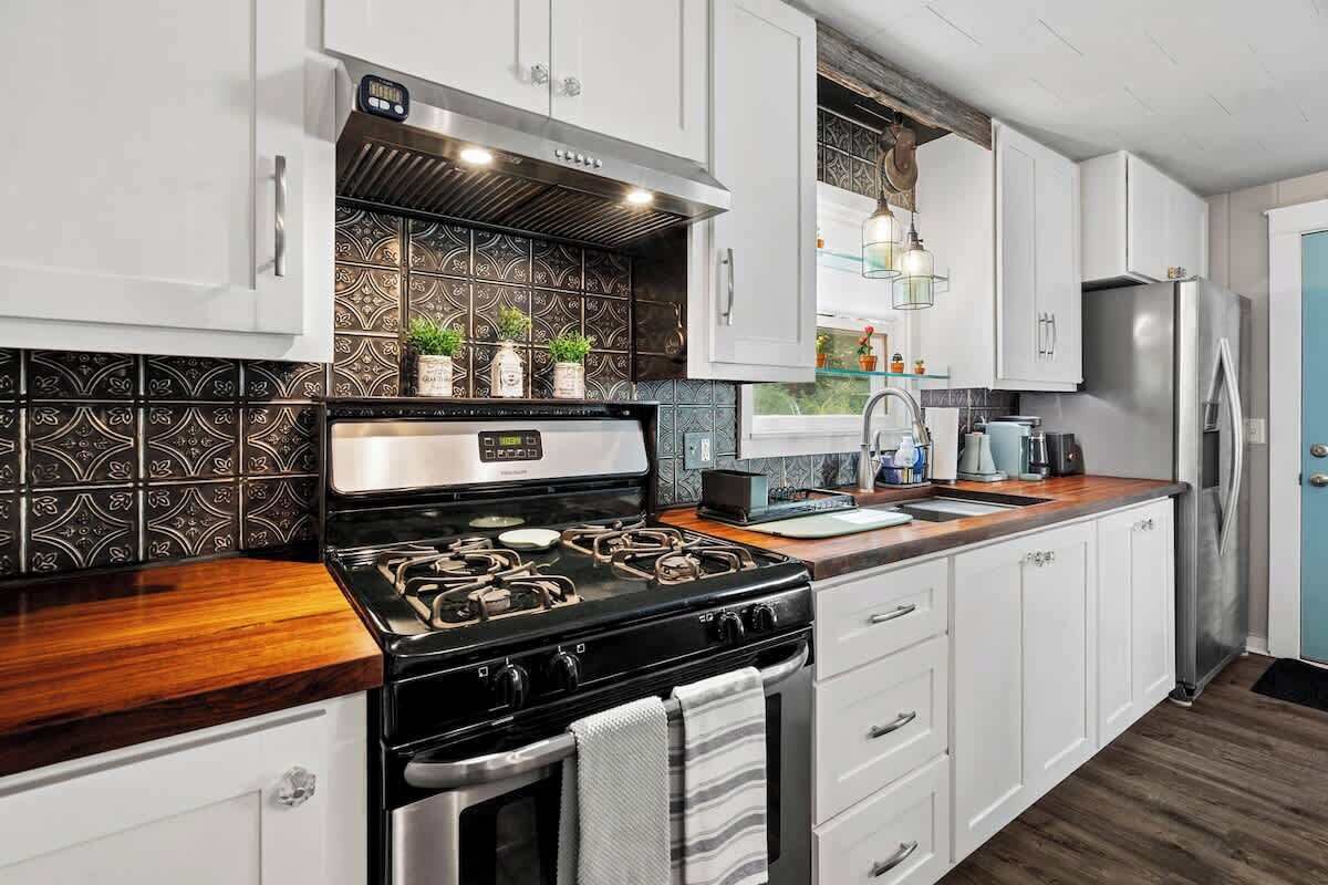 A kitchen with white cabinets, a black stove, and patterned backsplash.