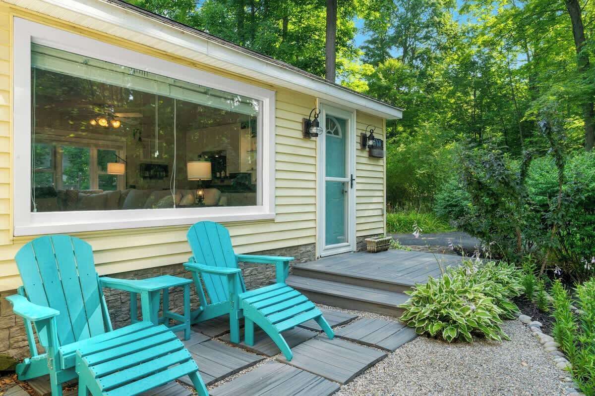 Una casa con un portico, due sedie e un giardino.