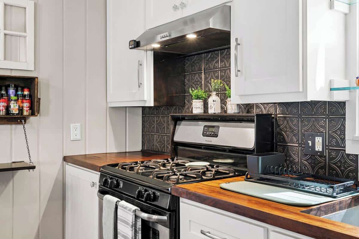 A kitchen with a gas stove, oven, and a backsplash with decorative tiles.