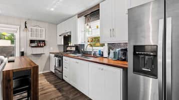Una cocina moderna con armarios blancos, un refrigerador de acero inoxidable y una encimera de madera.