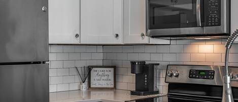 Una cocina moderna con electrodomésticos de acero inoxidable, incluyendo un refrigerador, microondas y horno.