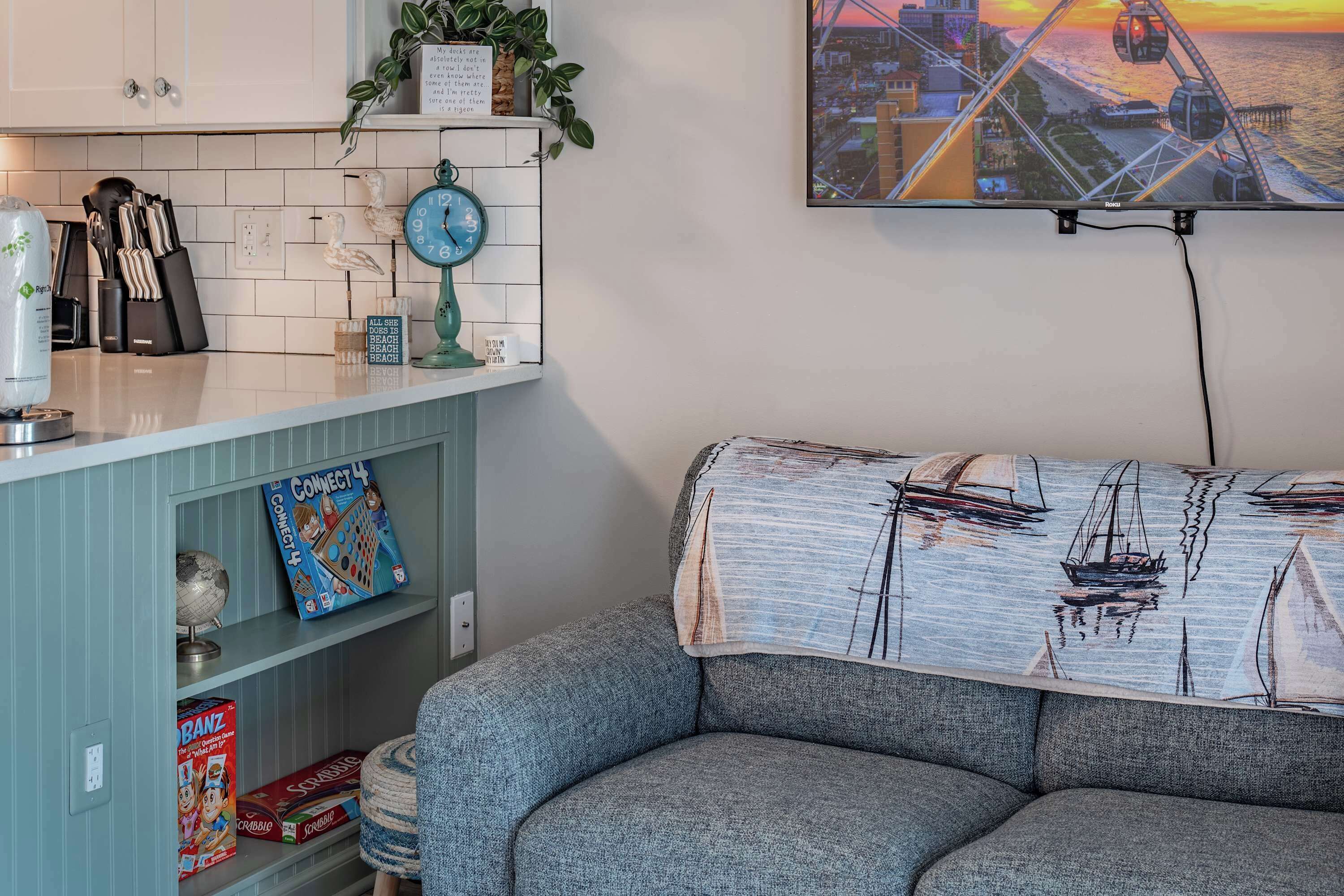 A living room with a sofa, a clock, and a bookshelf with games and a globe.