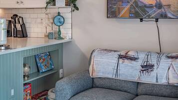 A living room with a sofa, a clock, and a bookshelf with games and a globe.