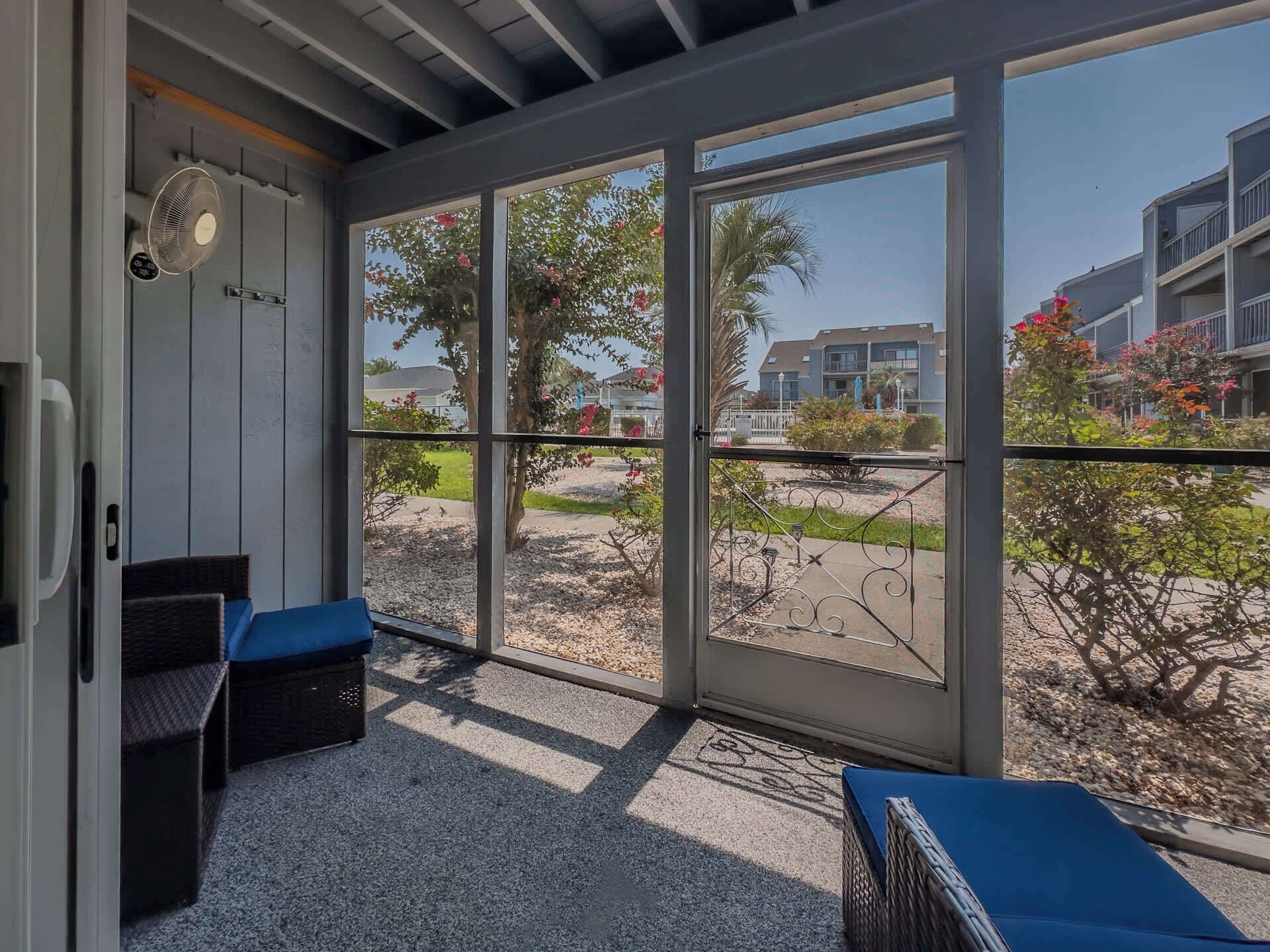 A room with a large window, a fan, and a seating area with cushions.