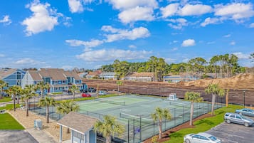 A residential area with houses, a tennis court, and a parking lot.