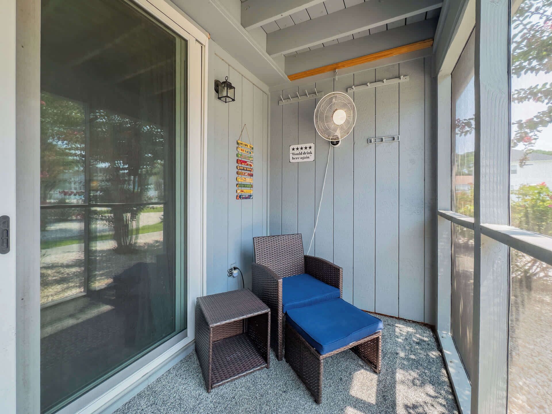 Un espace de véranda abritée avec une chaise en osier et une petite table, un ventilateur fixé au mur, et un panneau indiquant une note de quatre étoiles.