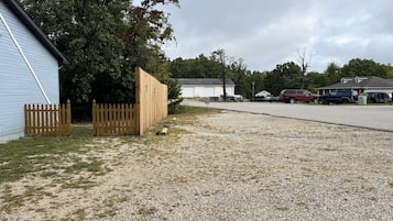 A gravel driveway leading to a building with a wooden fence and a parked car.